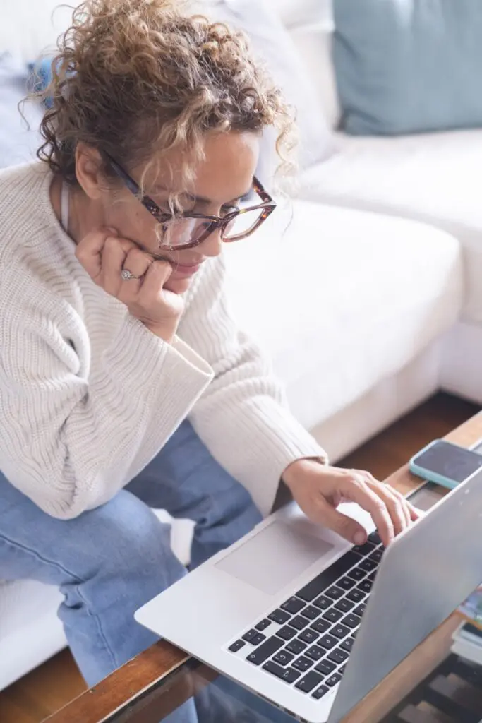 Woman researching using a laptop while sitting at home on a couch