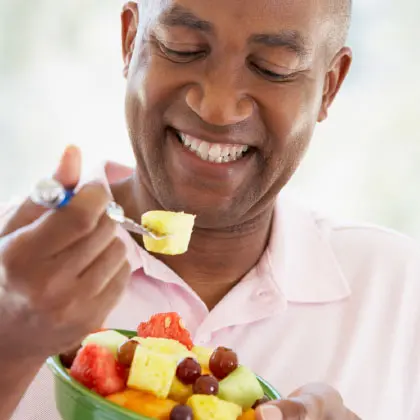Man eating cut up fruit from a bowl